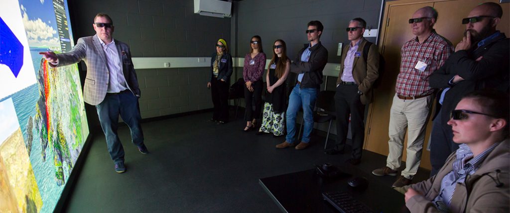 Group of people viewing large screen showing 3D images