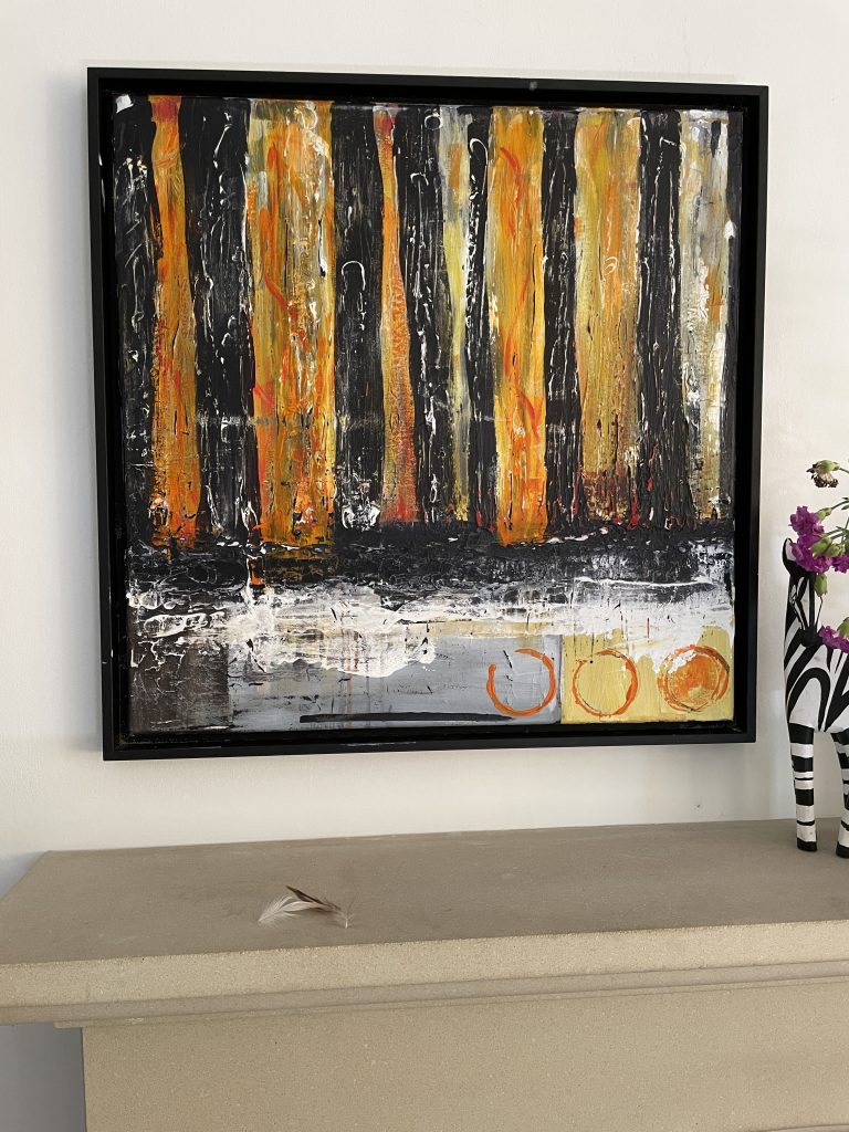 Wide black and orange stripes from the top to one third down. White streaks on the black and deeper orange on the other stripes.
Across the bottom third, on the left side is a dark square followed by a grey long rectangle with a pale orange rectangle. Where these colours meet the stripes there is a scrapping of white